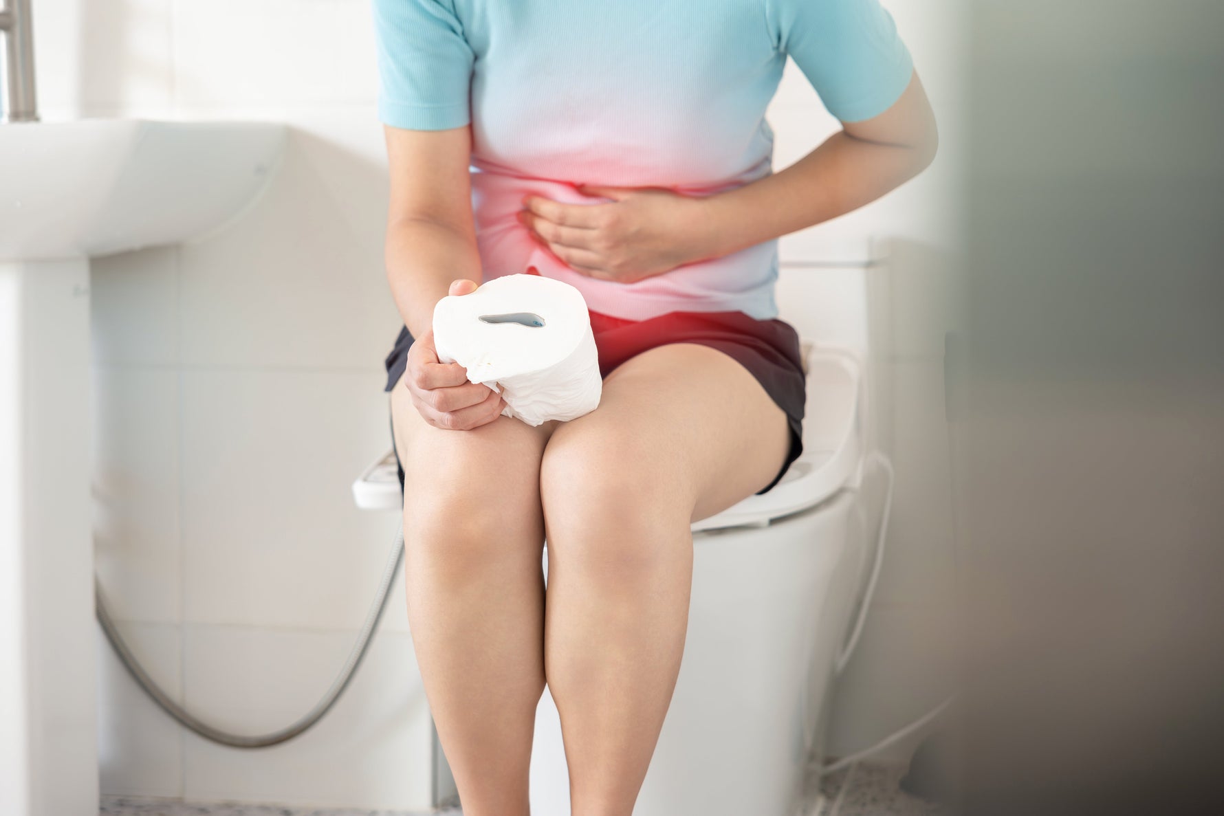 Person sitting on toilet holding stomach in discomfort, illustrating digestive side effects from low-quality magnesium supplements