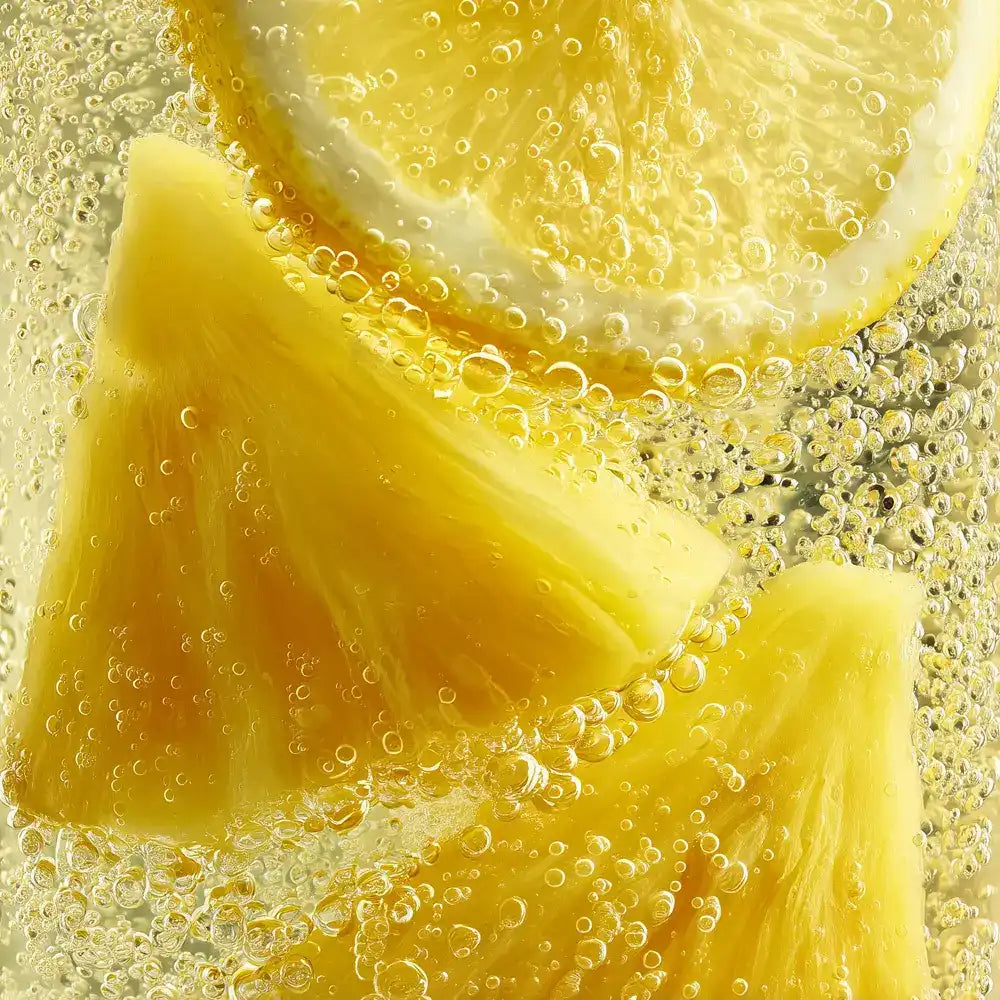 Lemon and pineapple slices in sparkling water with bubbles, refreshing citrus drink
