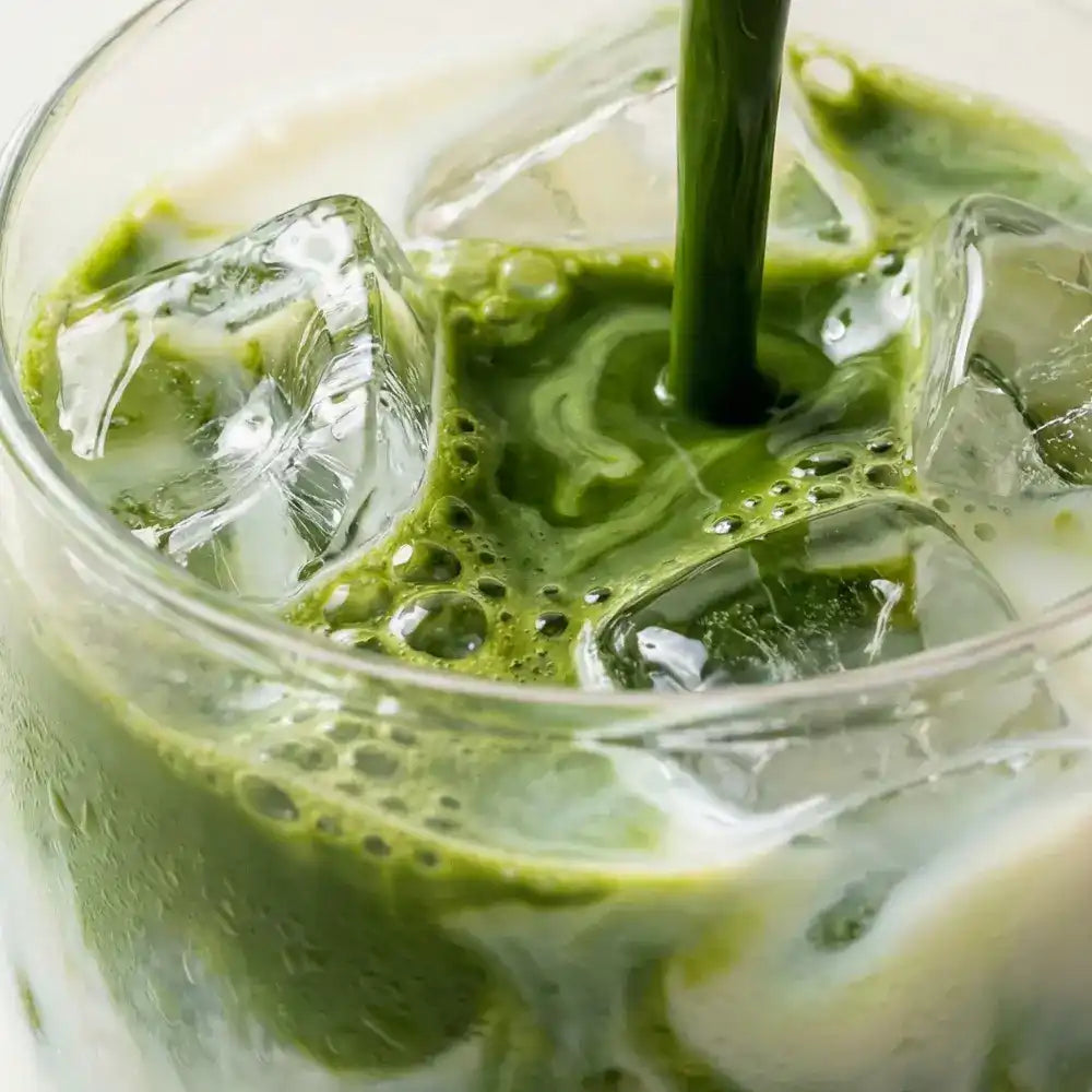 Close-up of iced matcha green tea latte with milk in a glass.