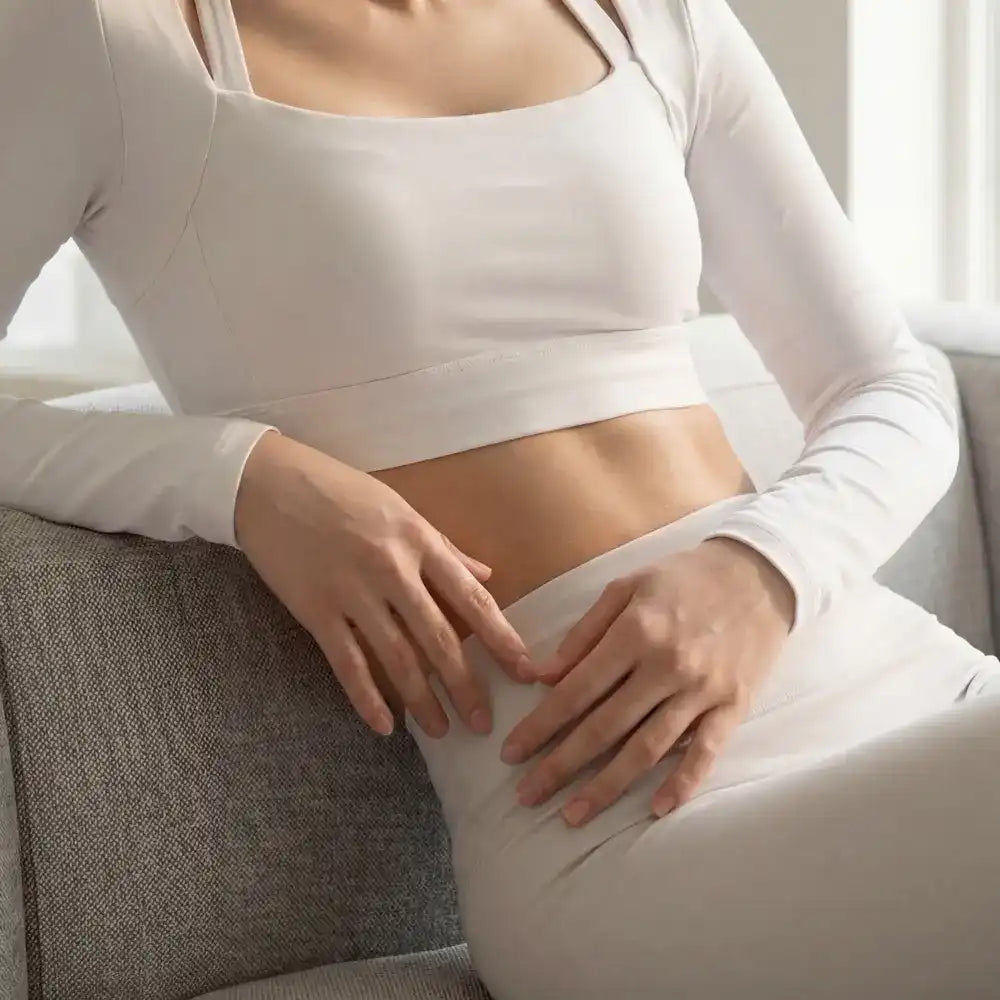 Woman in light lounge wear relaxing on a sofa, highlighting wellness and comfort