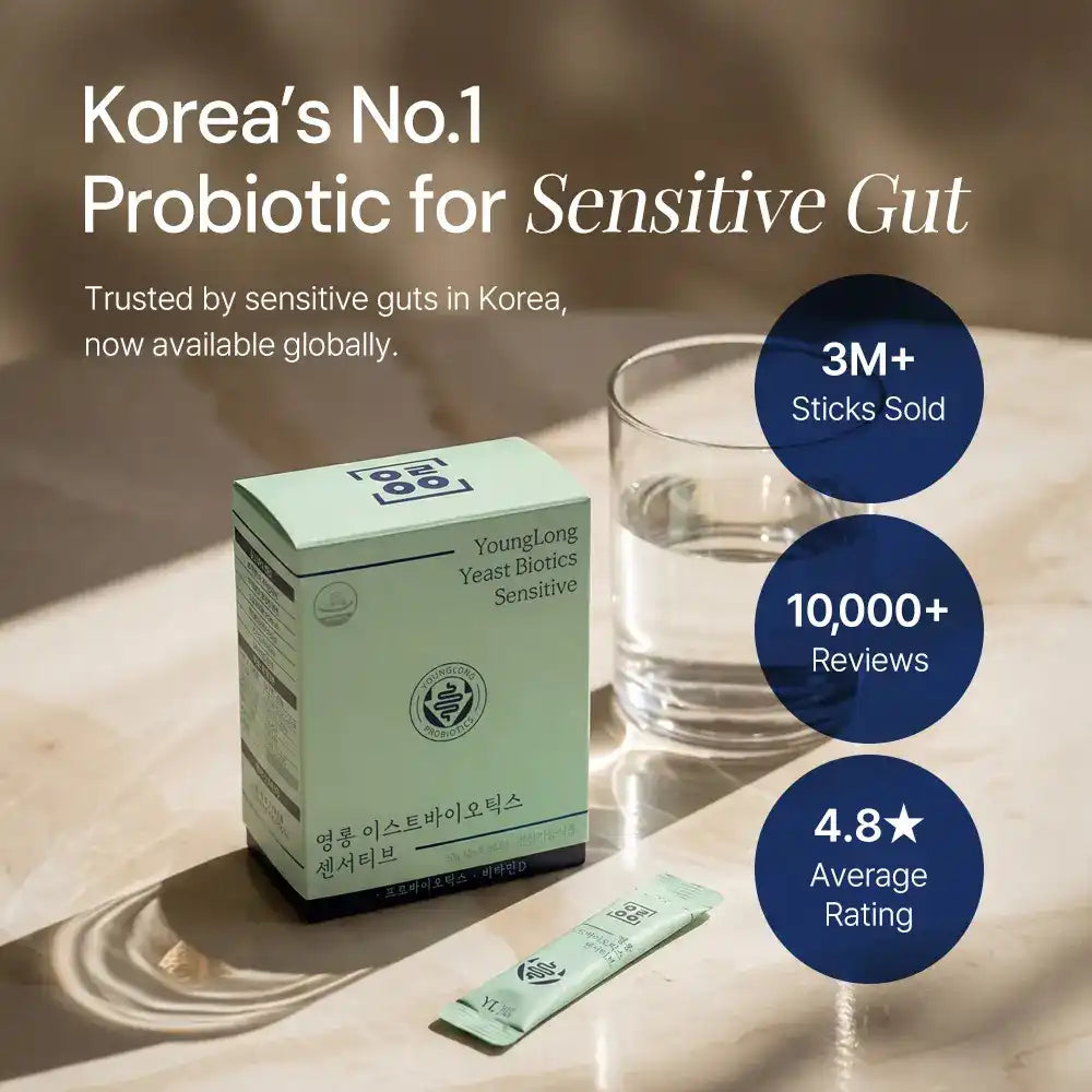 Probiotic supplement box labeled Yeast Biotics Sensitive with stick pack and glass of water on table